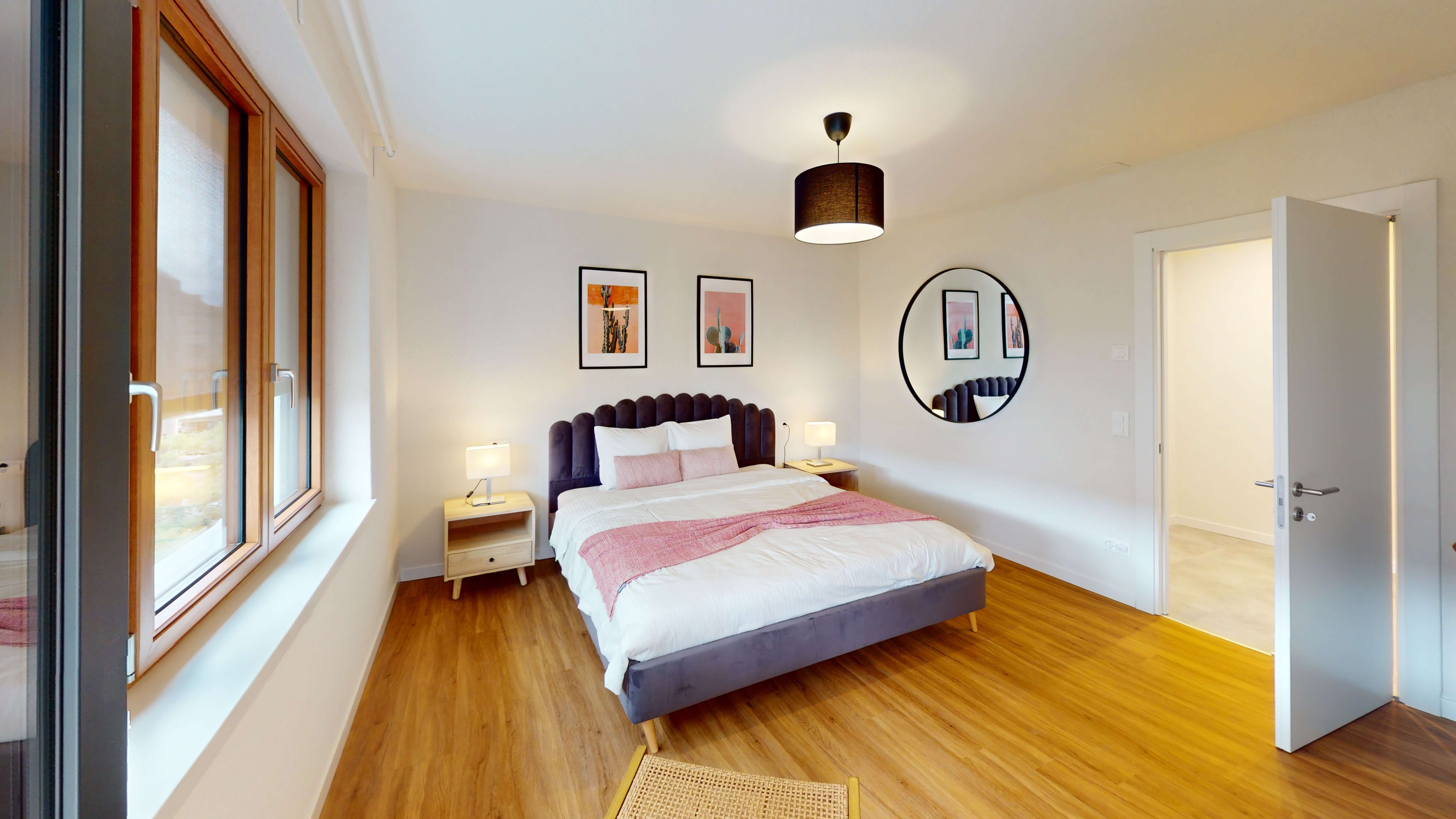 Bright bedroom in a Zurich apartment with a double bed, modern décor, and natural light